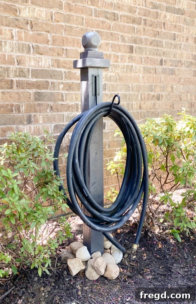 Beautifully finished DIY Water Hose Post holding a garden hose