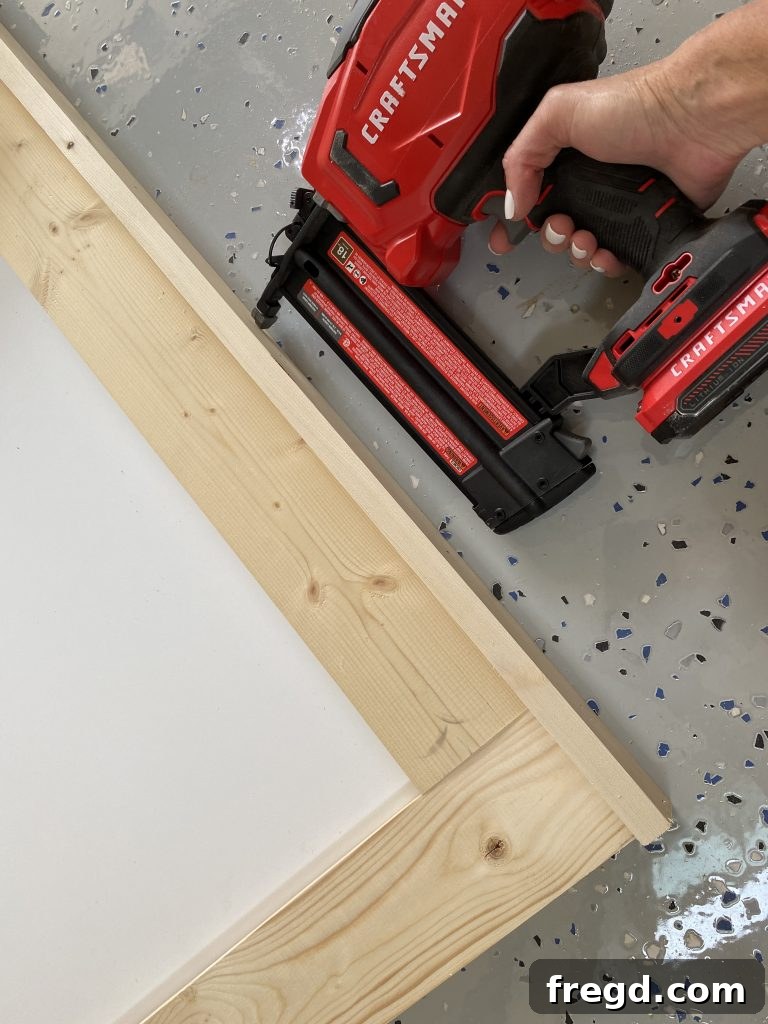 Your DIY Dry Erase Canvas 13 Side trim piece being attached to the wooden frame of the dry erase board