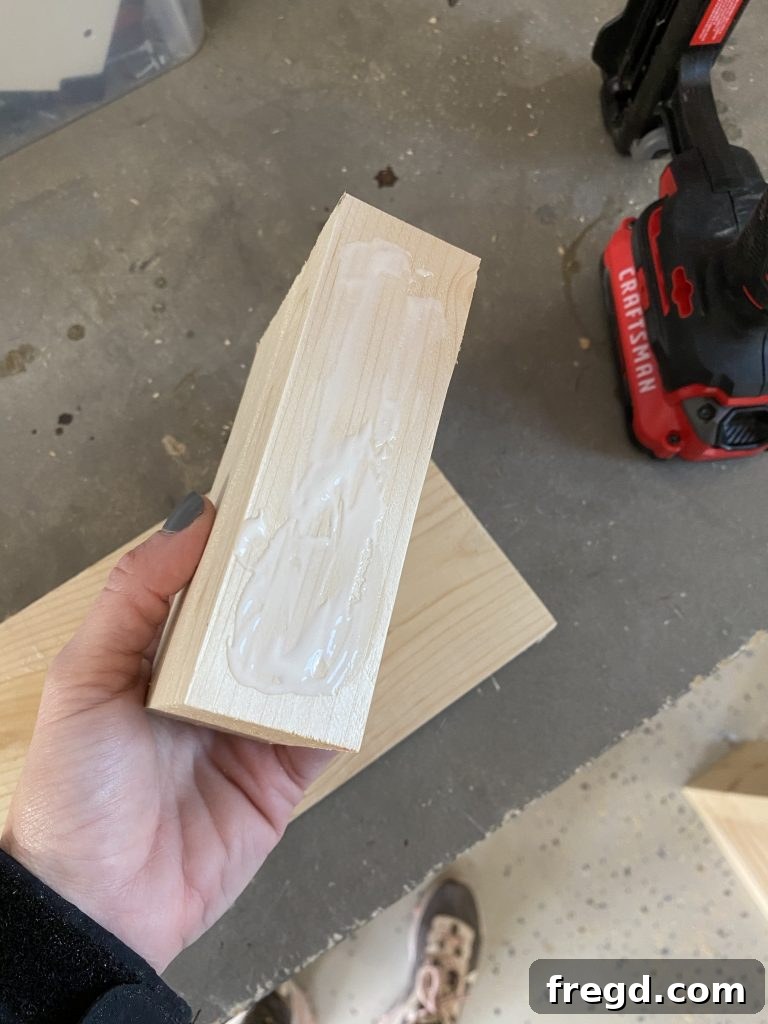 Applying a bead of wood glue to the end grain of a side piece, ensuring strong adhesion for the joint.