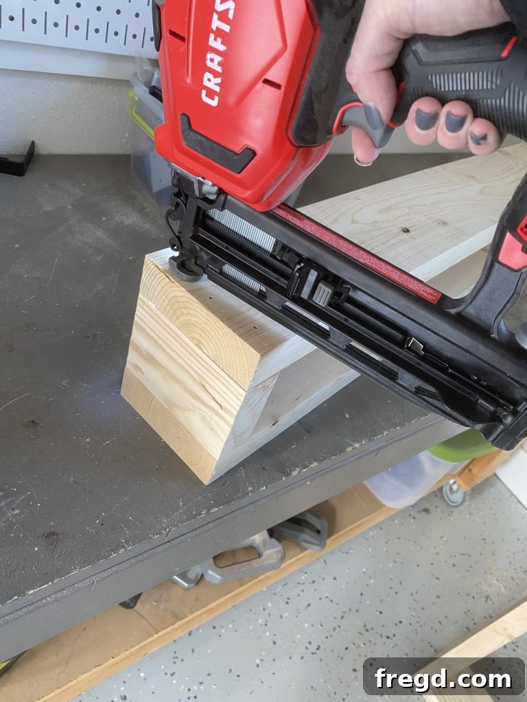 Attaching the back 2x6 board to the two side pieces with wood glue and brad nails, completing the box structure.