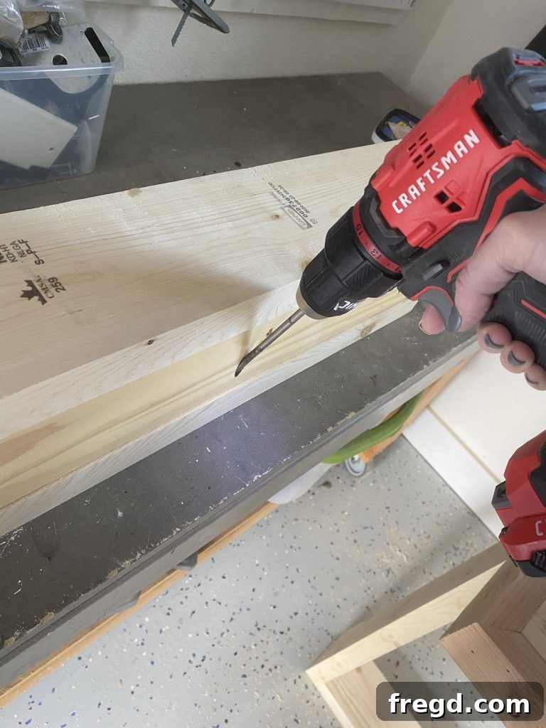 Attaching the 1x4 base board to the inside of the stocking holder box using pocket hole screws and wood glue.