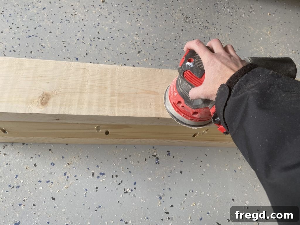 Using an orbital sander to smooth the surface of the assembled wooden stocking holder, preparing it for painting.