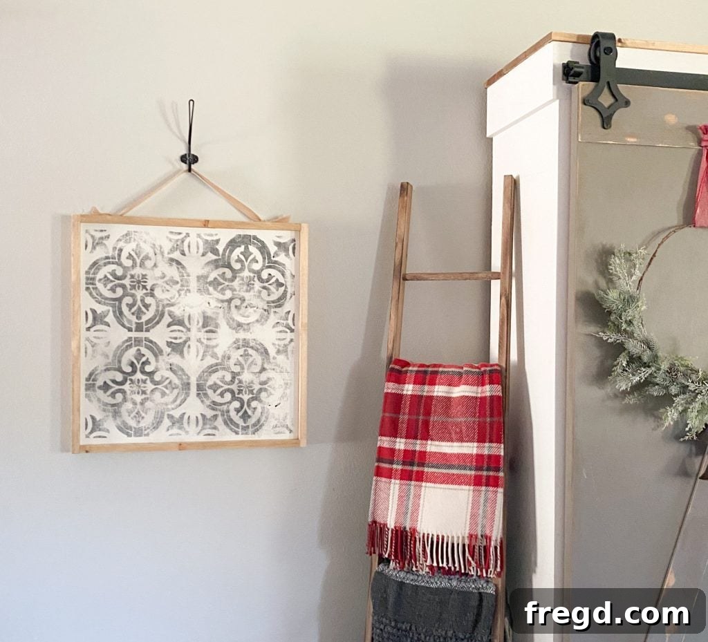 Close-up of the DIY stenciled wall art showcasing the detailed stencil work, distressed texture, and rustic wooden frame.