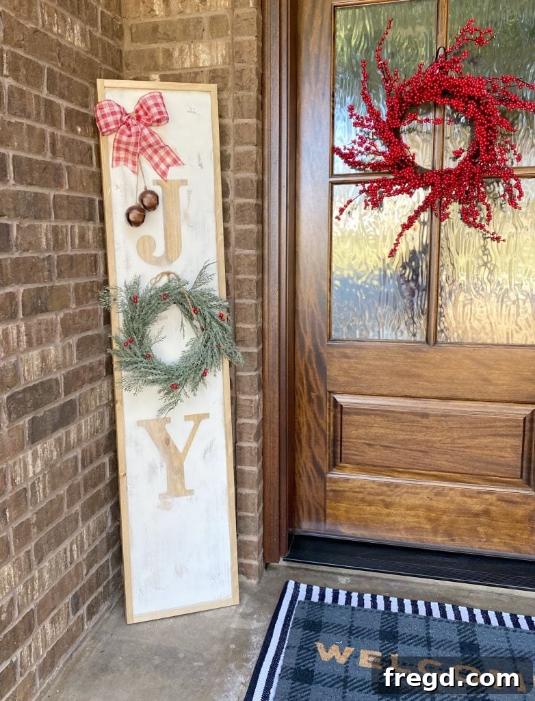 Beautifully crafted JOY reversible porch sign, rustic white with stained wood letters, adorned with a burlap bow and jingle bells.