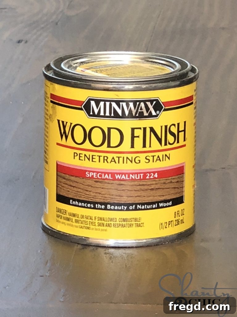 Wood board being stained with Minwax stain using a wiping rag, showing even color application.