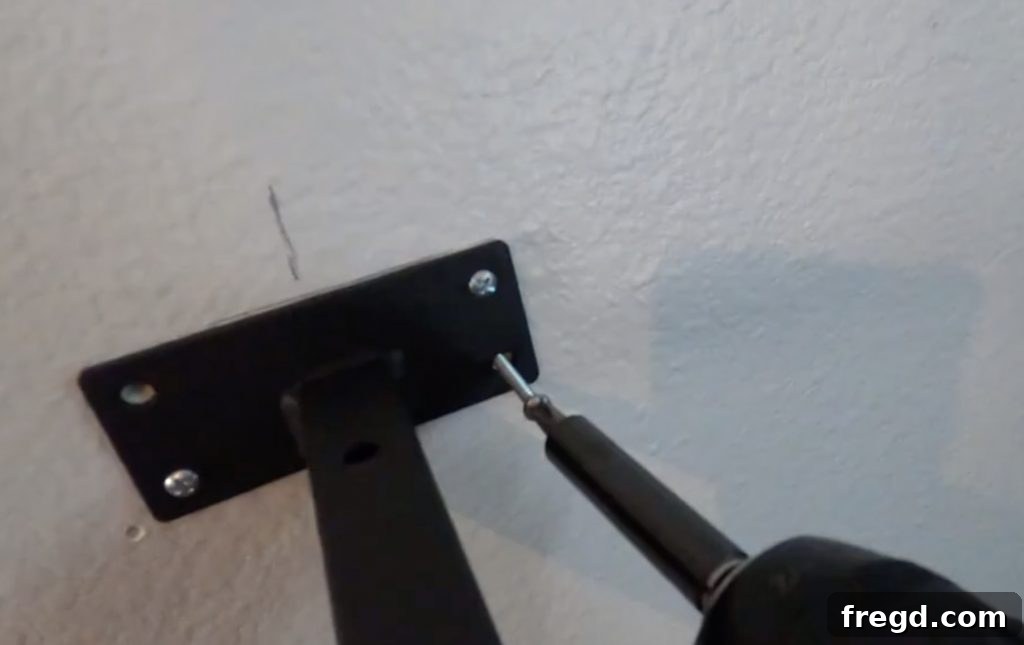 Inexpensive DIY Wall Shelves 11 A metal shelf bracket being screwed into drywall anchors, securing it to the wall