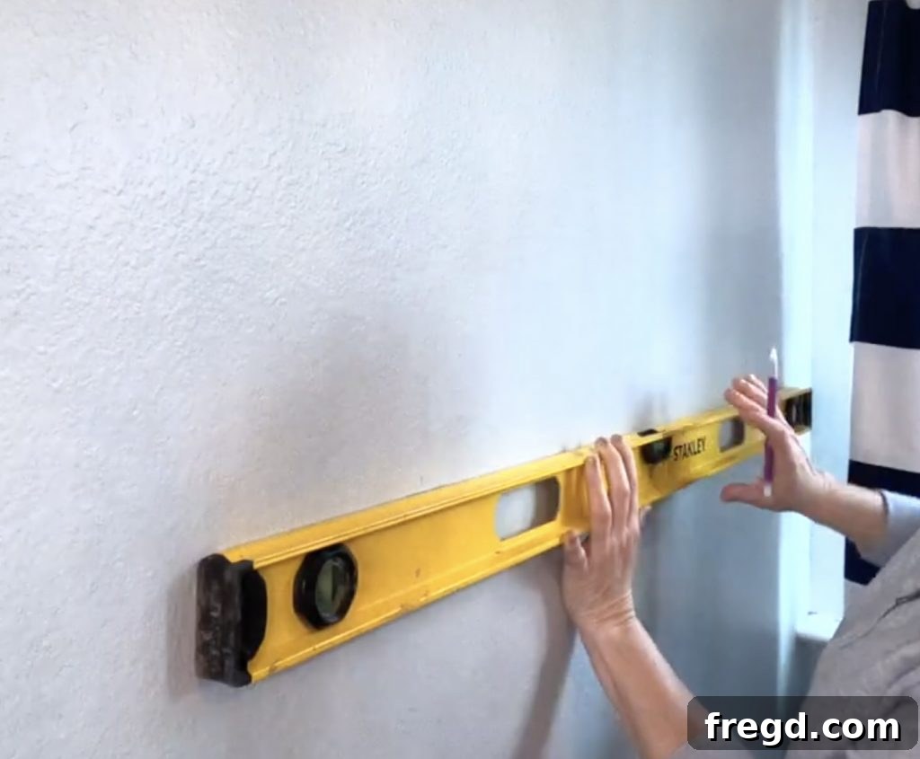 Inexpensive DIY Wall Shelves 9 Using a spirit level to mark the level position for the second shelf bracket on a wall