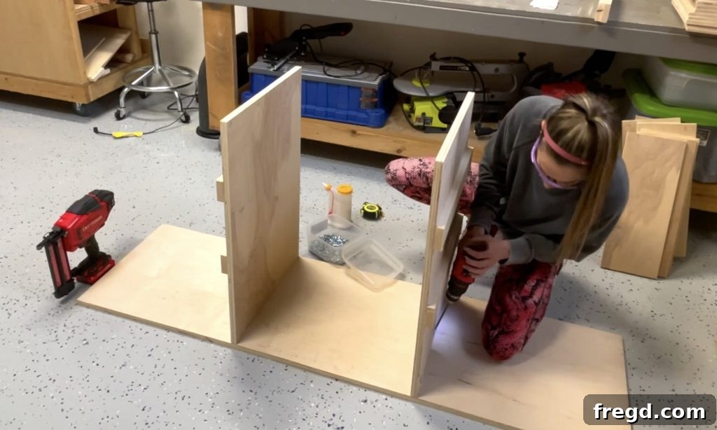Attaching vertical dividers to the bottom cabinet board using pocket hole screws and wood glue.