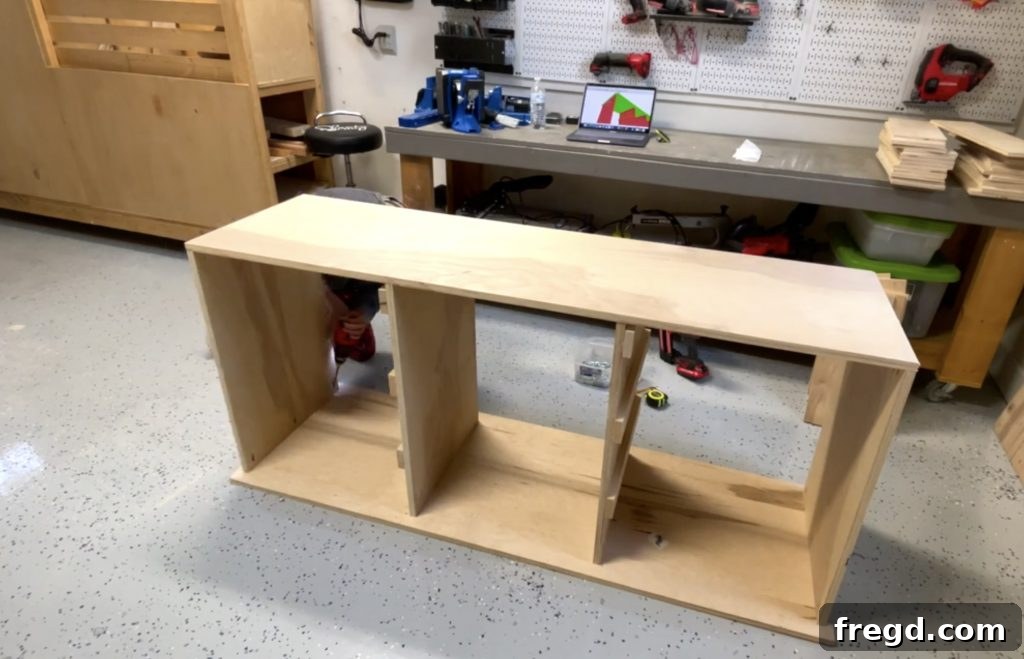 Attaching the cabinet top piece to the dividers with pocket hole screws and wood glue.