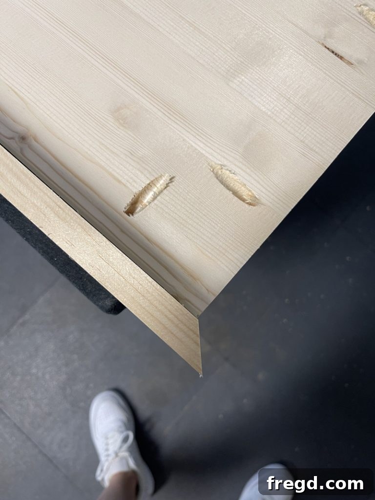 Using a Kreg pocket hole driver to secure a trim board to the tabletop, demonstrating strong, concealed joinery.