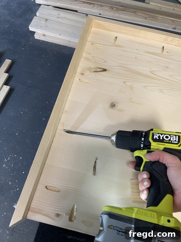 Attaching the final short trim piece to the tabletop, completing the mitered frame.