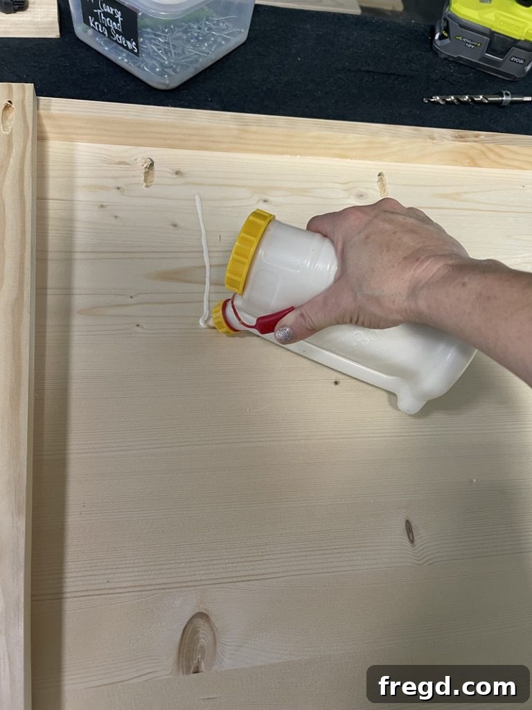 Applying wood glue to the underside of the tabletop where a center support board will be attached.