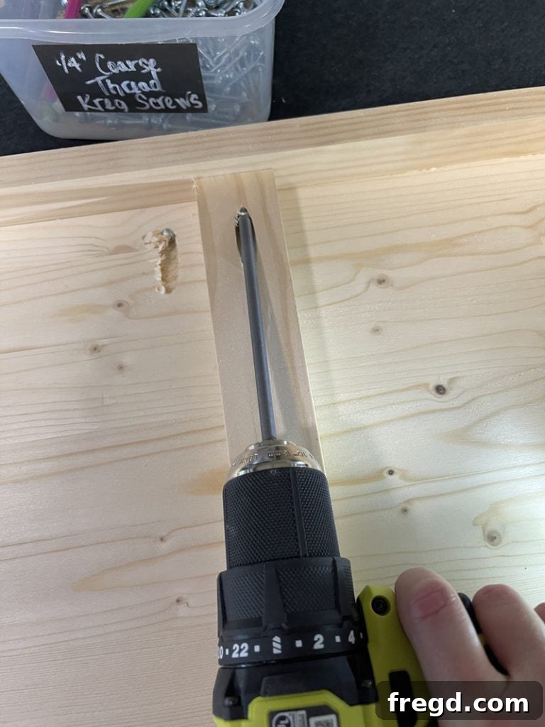 Securing a center support board with Kreg pocket hole screws to the table's trim, demonstrating strong internal joinery.