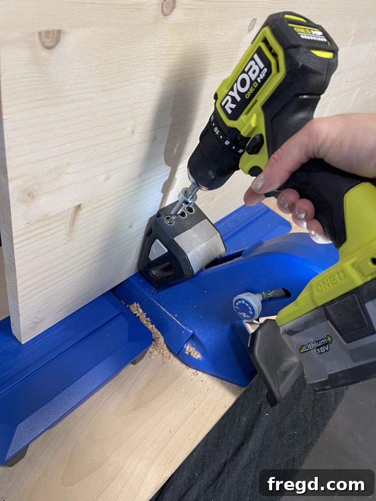 Wood panel on a workbench with a Kreg pocket hole jig set up for drilling.