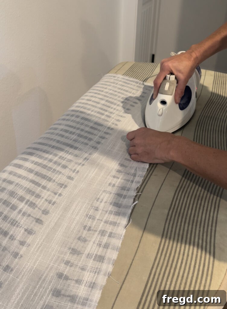 Close-up of fabric tape being applied to a hemmed edge with an iron