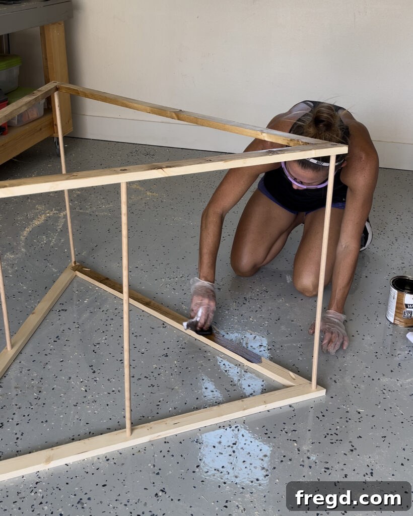 Applying wood stain to the assembled doghouse bed
