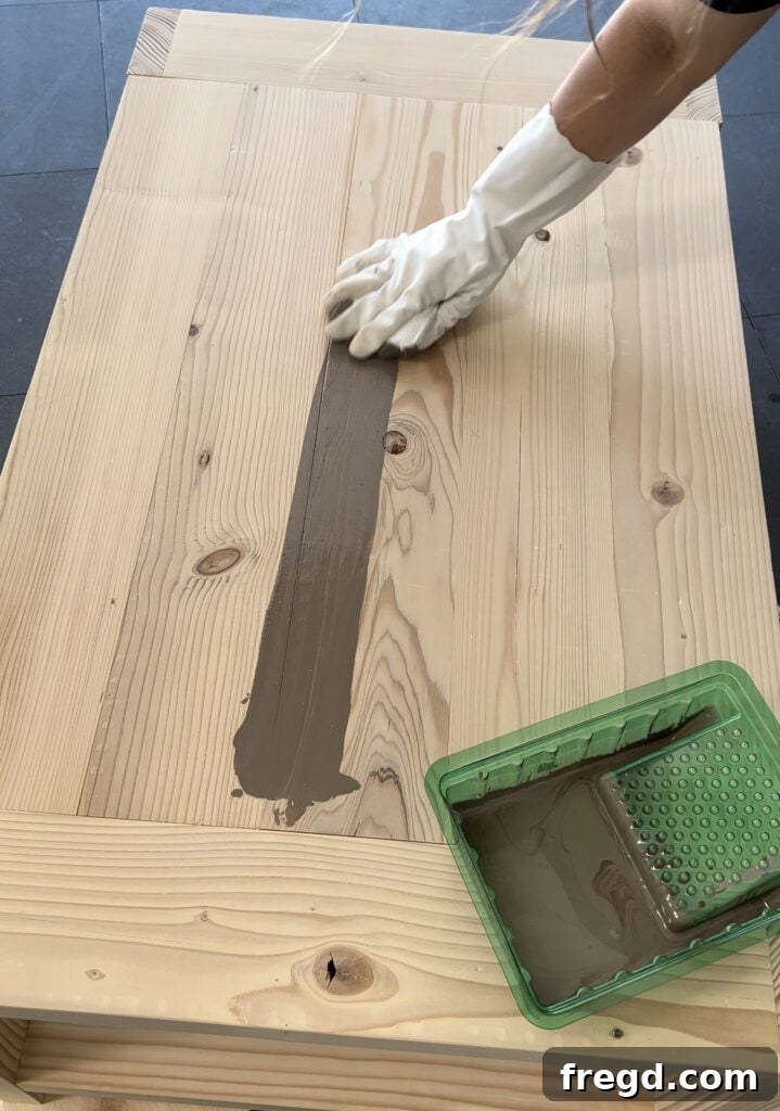 Craft Your Seven-Board Coffee Table 18 Applying custom mixed wood stain to the DIY coffee table, highlighting the wood grain and achieving the desired finish.