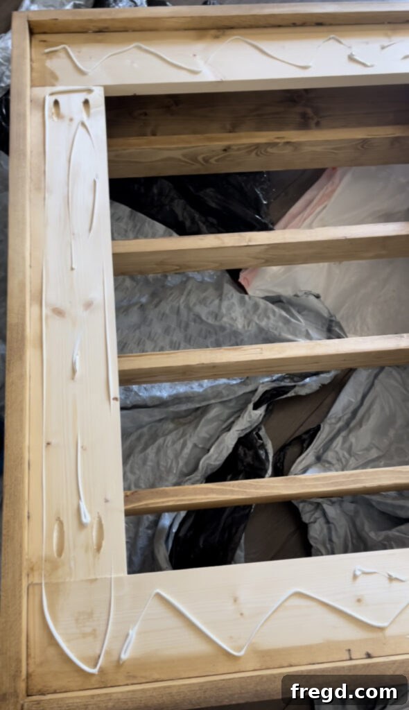 Elevate Your Bathroom with DIY Mirrored Storage 17 Shows construction adhesive being applied to the mirror frame before the mirror is placed.