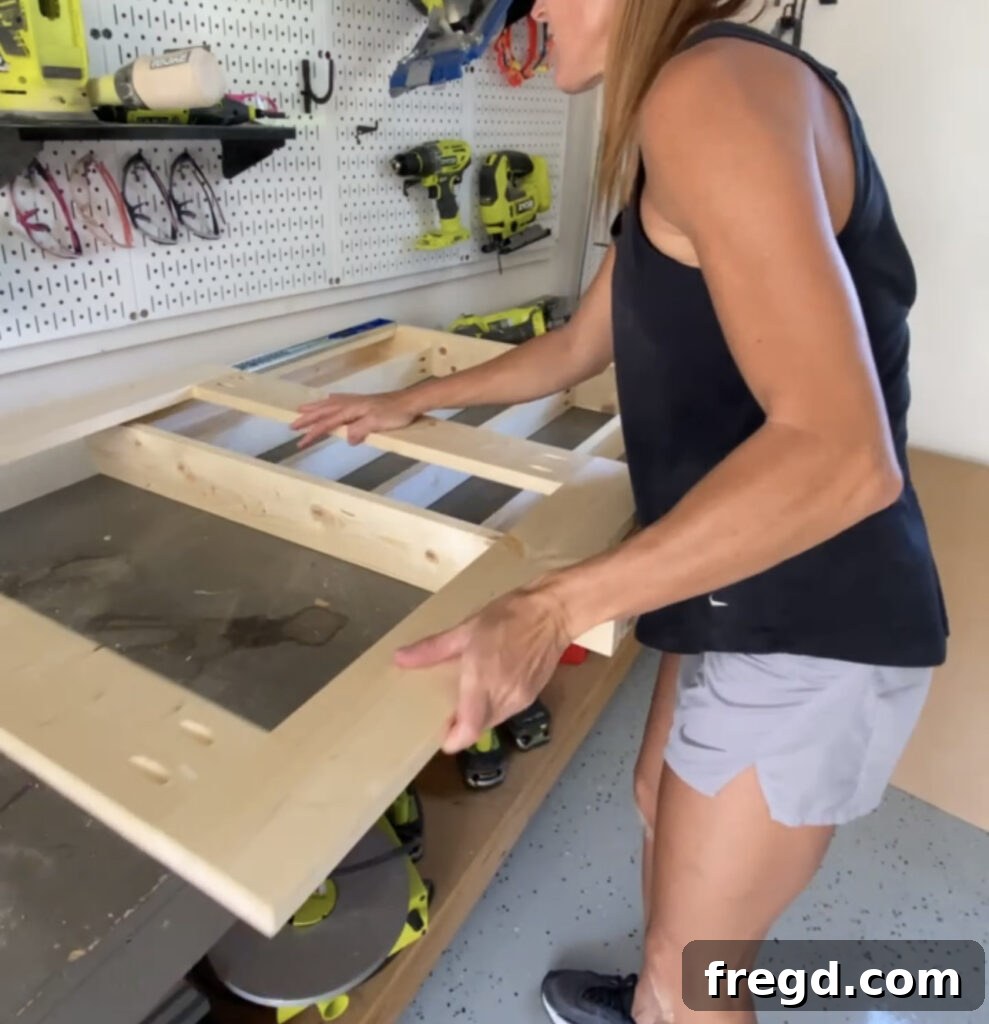 Elevate Your Bathroom with DIY Mirrored Storage 11 Shows the act of sliding the mirror frame onto the cabinet frame's drawer slides to assemble the unit.