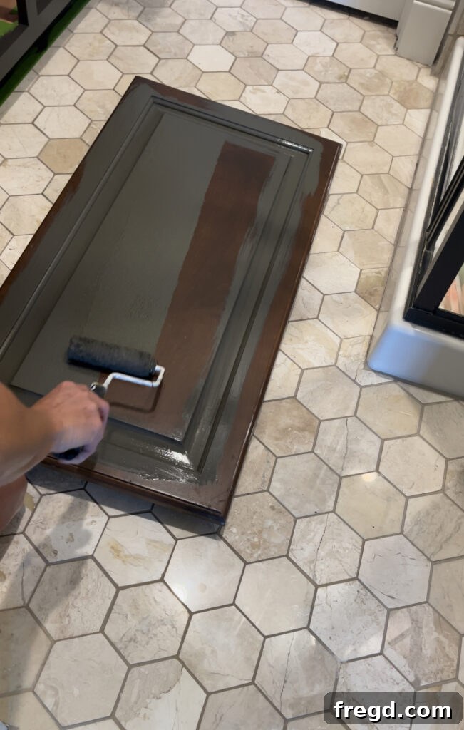 Using a paint brush and roller to paint cabinet doors