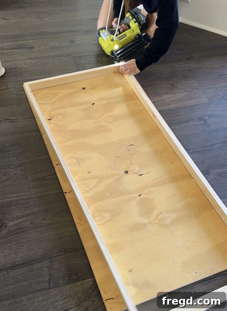 Wooden frame being assembled with wood glue and brad nails.