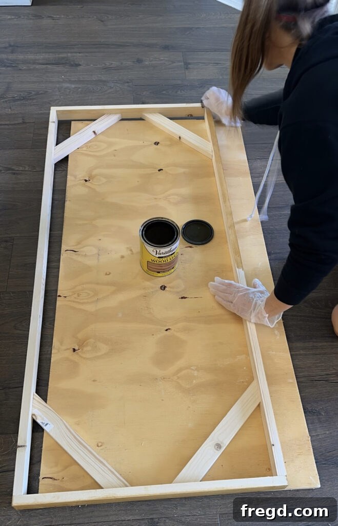Applying wood stain to the newly assembled custom frame.