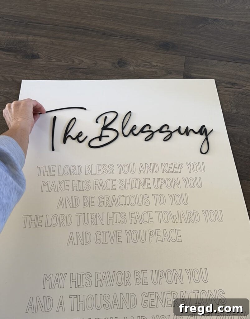 Applying glue to the back of the cut words before attaching them to the scored sign board.