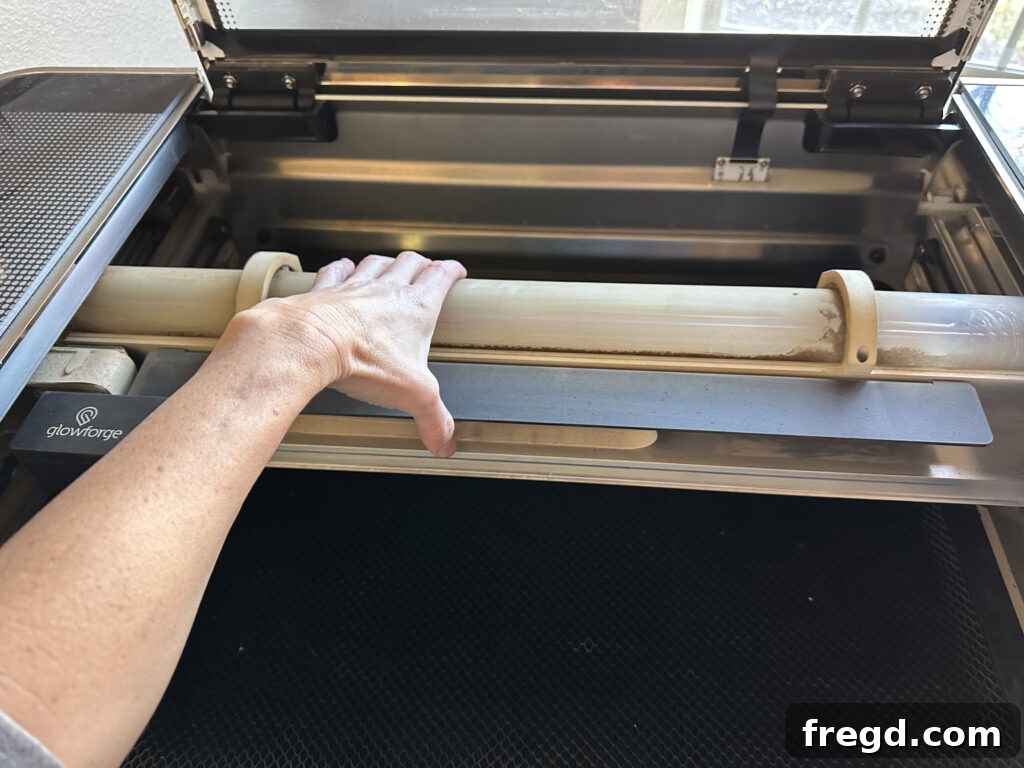 Hand gently moving the laser tube inside the Glowforge to access back plate screws.