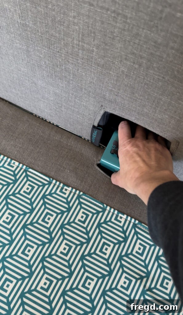 A blue clamp being inserted into a slit on a Lovesac Sactional piece, illustrating how components are locked together.