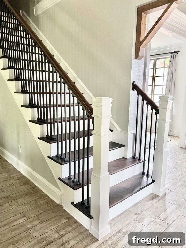 The completely renovated staircase with black balusters, dark stained treads, and white risers and newel posts.