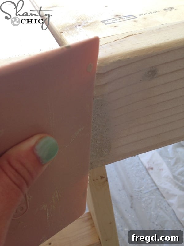 Using wood filler and a putty knife to conceal exposed screw holes on the outdoor chair.