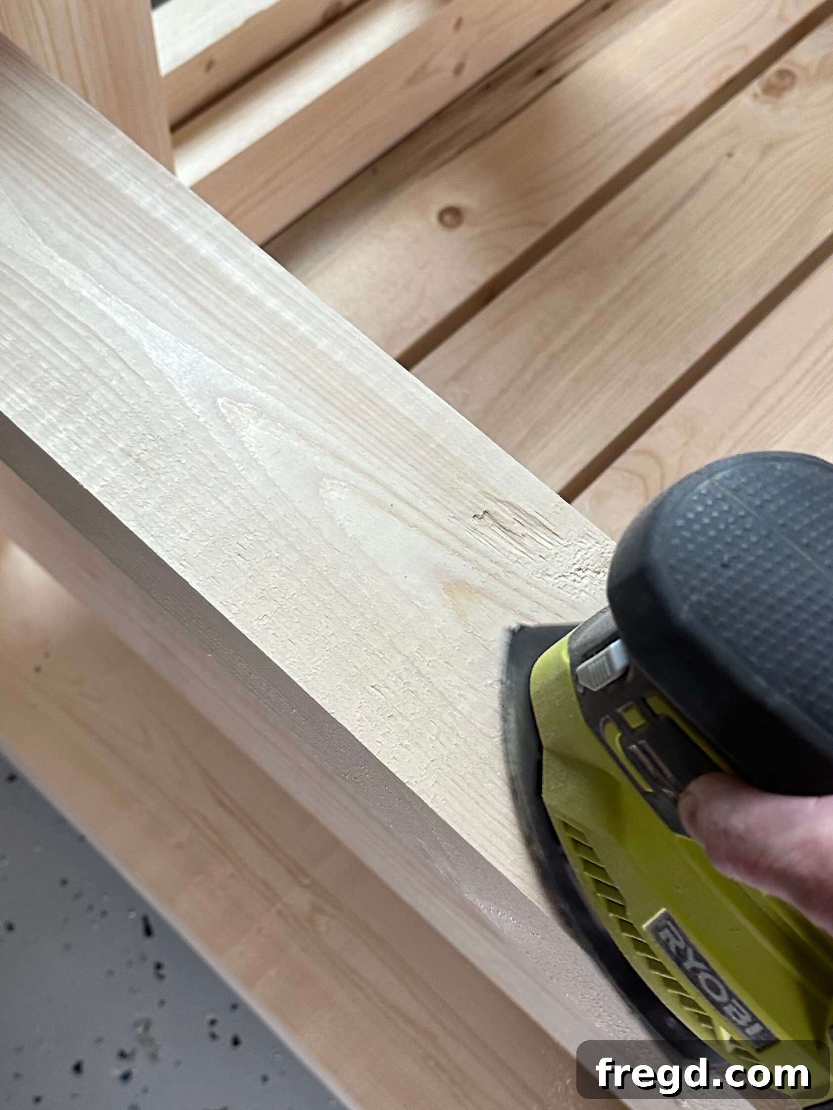 Sanding the entire outdoor chair for a smooth finish, using 120-grit and 220-grit sandpaper.