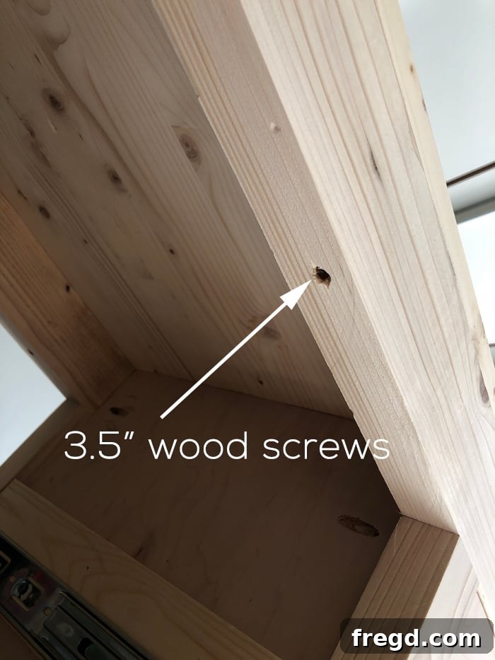 Craft Your Own Modern Farmhouse Sideboard 20 Underside view of the cabinet top being secured to the frame, showing screw placement.