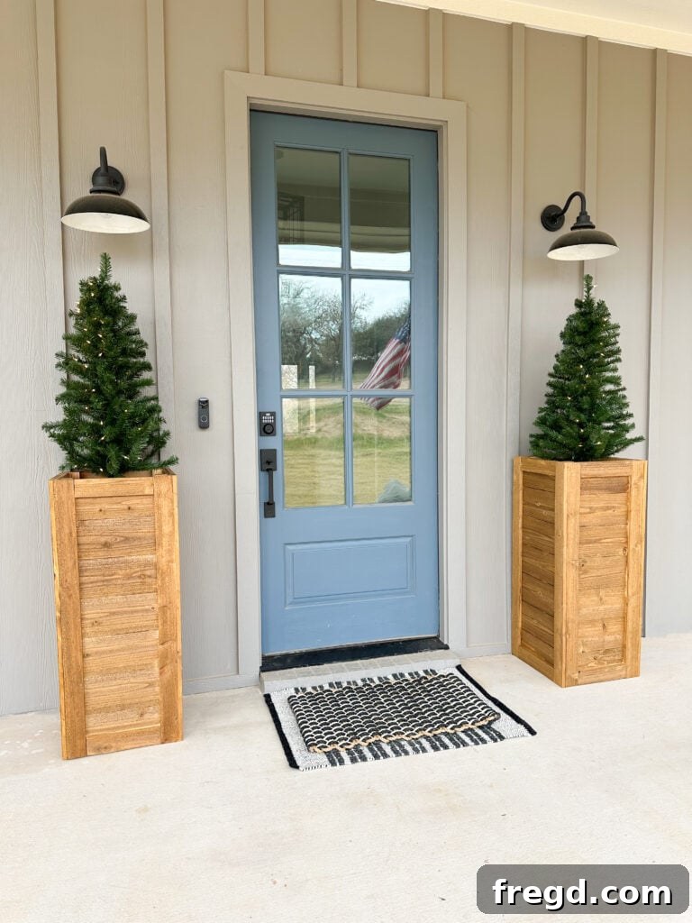 A pair of elegant cedar planter boxes adorned with winter foliage and festive string lights, gracing a front porch.