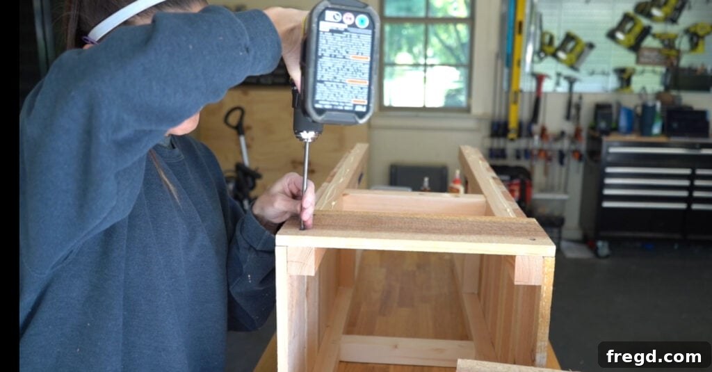Attaching long cedar slats to the remaining sides of the planter, aligning them flush with the previously installed short slats.