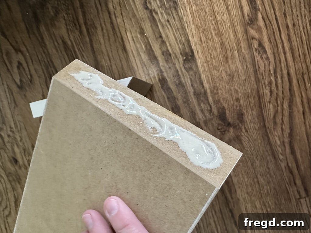 Applying wood glue to the mitered edges of the trim block pieces.