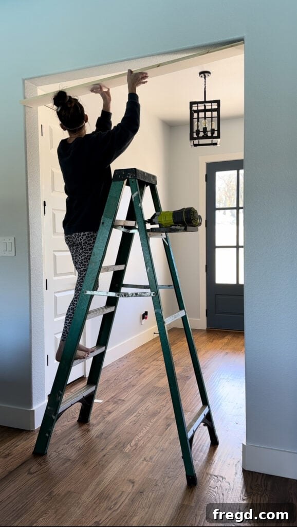Applying liquid nails adhesive to the back of the top frame board before installation.