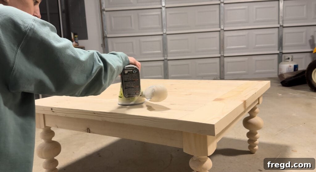 Sanding the coffee table top with an orbital sander for a smooth finish