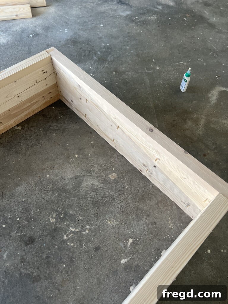 Build Your Own Twin Platform Bed 15 Another view of the bed frame assembly process, connecting side to footboard.