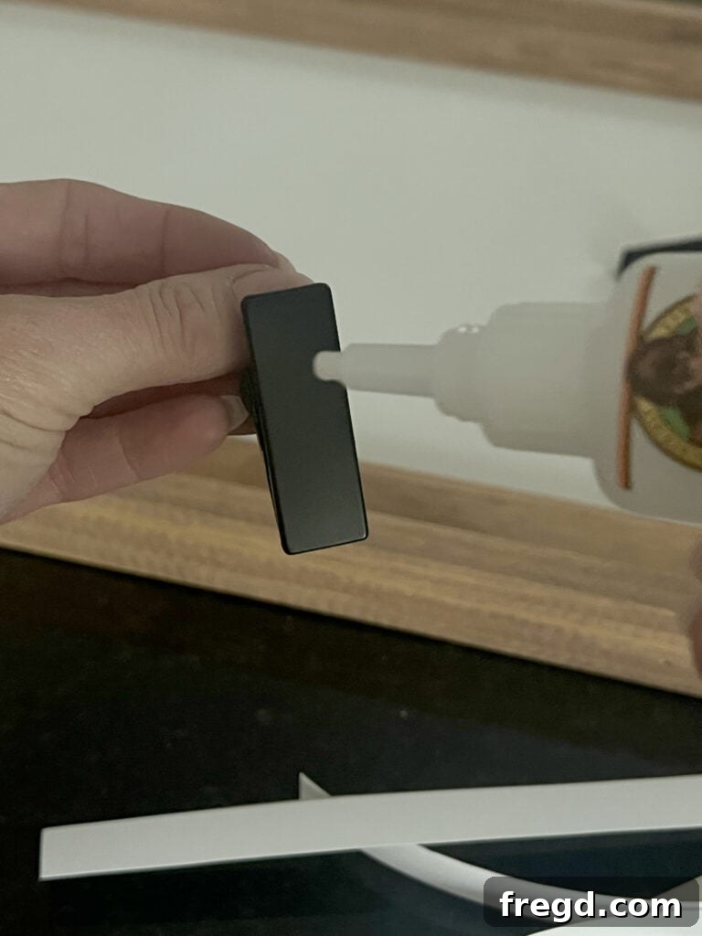Close-up of a black metal clip securely glued to the canvas panel, ready to hold artwork.