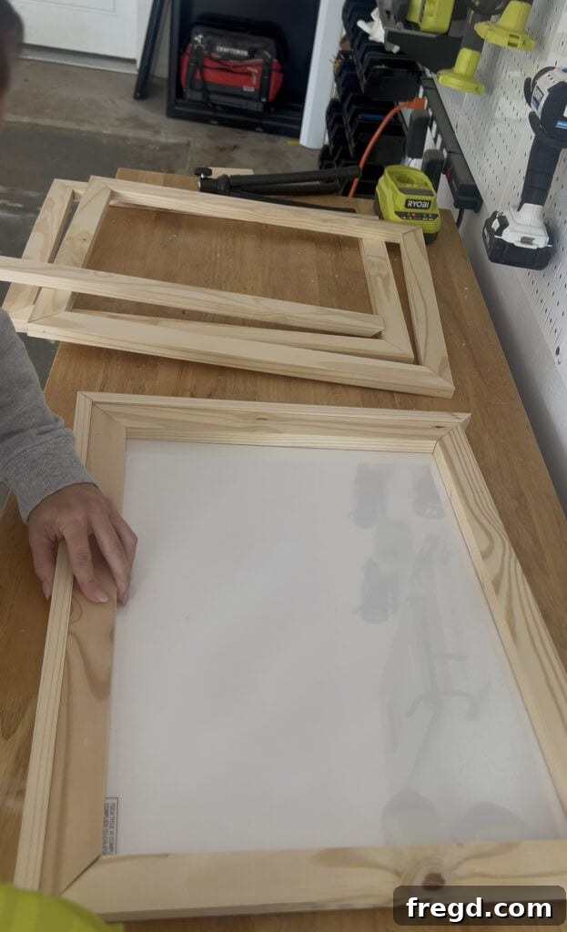 An assembled inner frame, elevated by scrap wood, with the outer frame pieces being attached using wood glue and brad nails, creating a recessed lip.