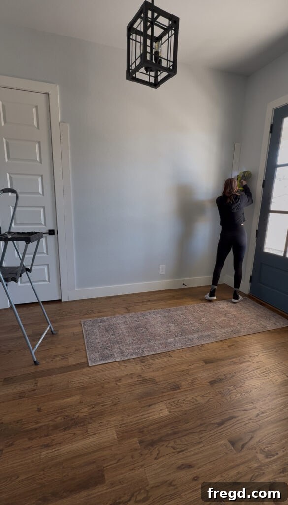 Removable Modern Accent Wall DIY for Renters 4 Attaching MDF trim to the wall with a finish nailer, targeting studs for secure installation.