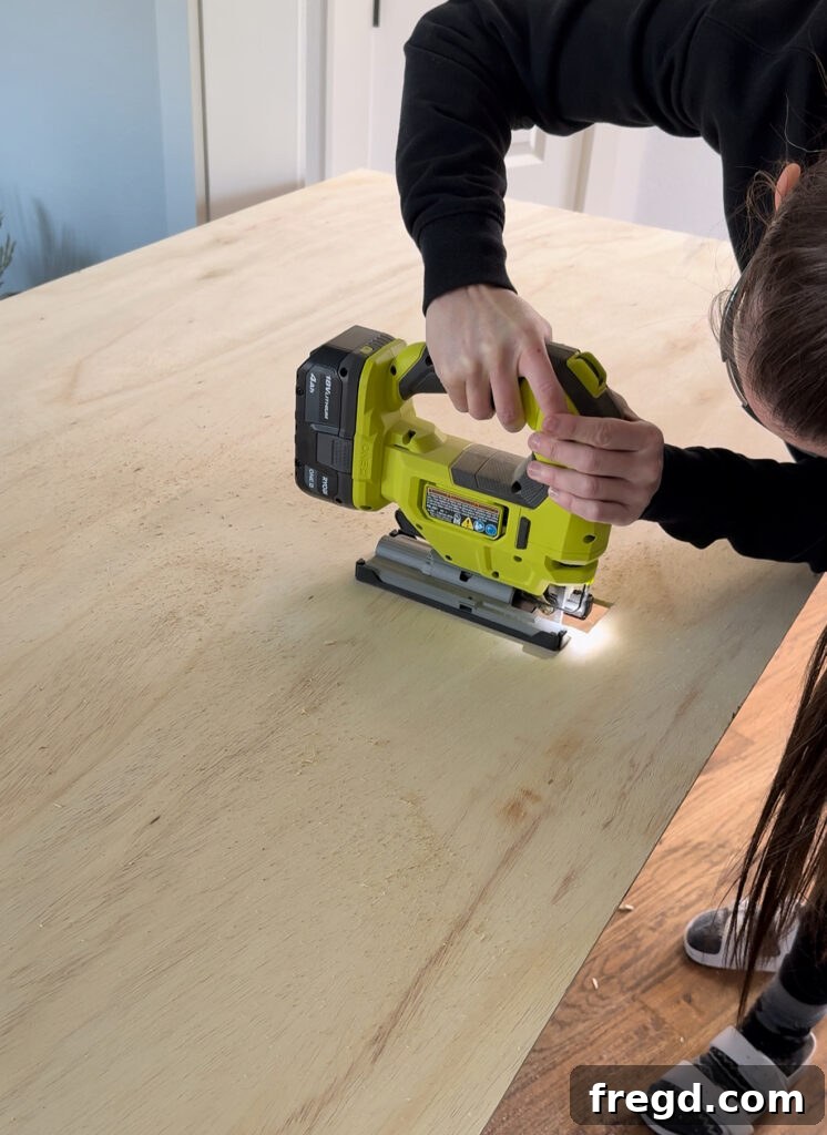 Removable Modern Accent Wall DIY for Renters 7 Marking and cutting an outlet hole in the plywood panel using a jigsaw.