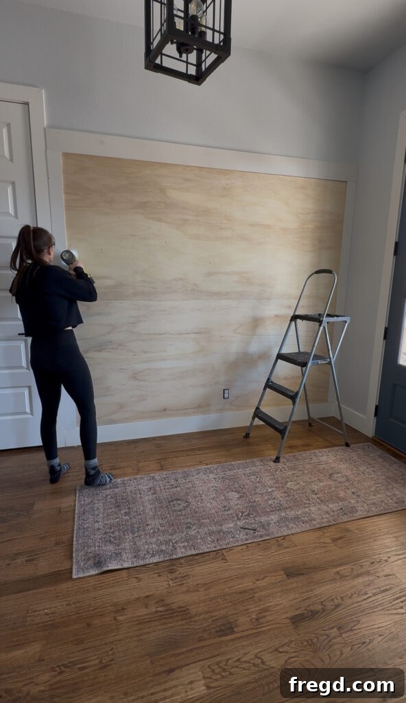 Removable Modern Accent Wall DIY for Renters 9 Attaching the top plywood panel with finish nails, completing the base of the accent wall.