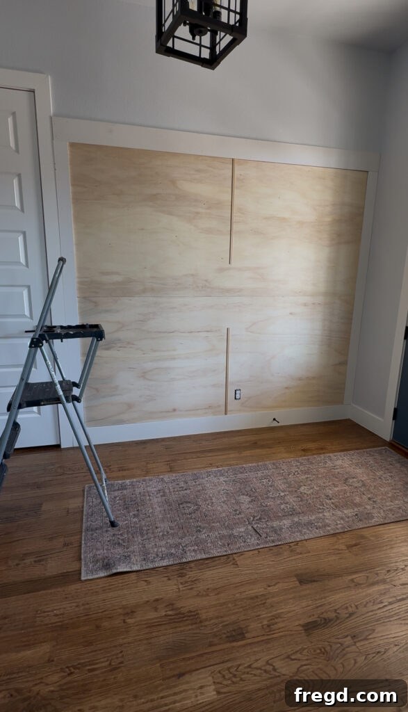 Removable Modern Accent Wall DIY for Renters 10 Attaching the vertical center screen moulding pieces to the plywood panel.