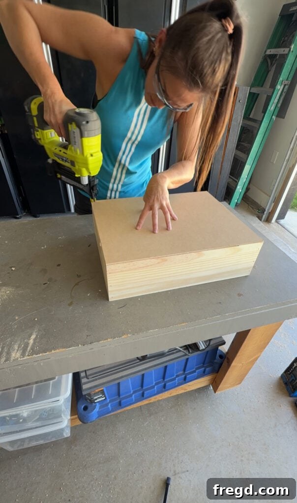 Easy Wood Nightstand Builds for Newbies 12 Plywood bottom being attached to the assembled drawer frame with staples and wood glue.