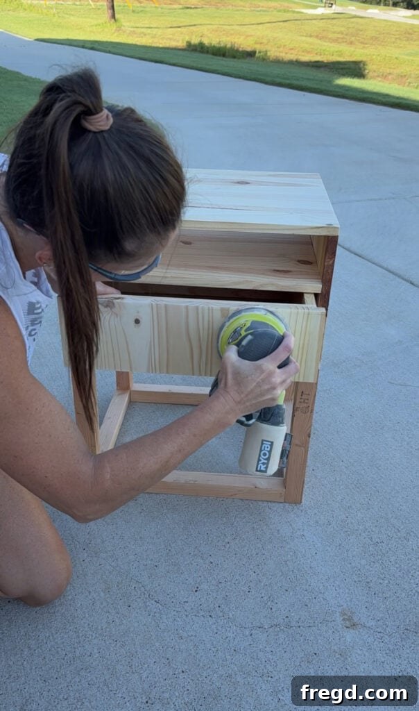 Easy Wood Nightstand Builds for Newbies 17 Sanding the DIY wood nightstand with a circular sander to achieve a smooth finish.