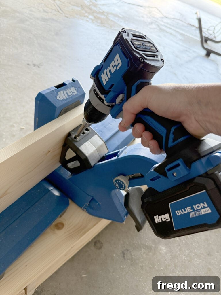 Ultimate DIY 4x8 Workbench With Free Plans 3 Close-up of a Kreg Jig in use, creating pocket holes in a piece of wood.