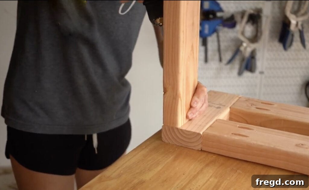 Attaching a long frame piece to one of the side assemblies, forming the initial structure of the DIY cowhide bench.