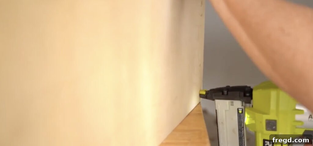 Stapling plywood side panels onto the sturdy DIY bench frame, creating a smooth surface for upholstery.